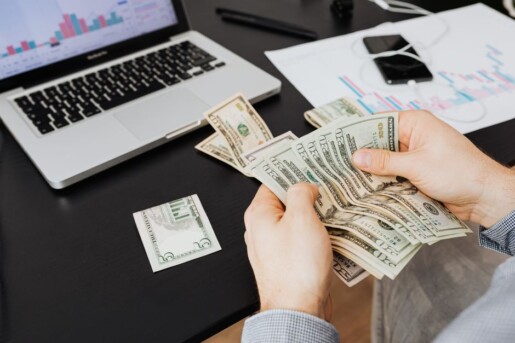 Notas de dólar ao lado de um notebook representando ganhos em moeda estrangeira pela internet