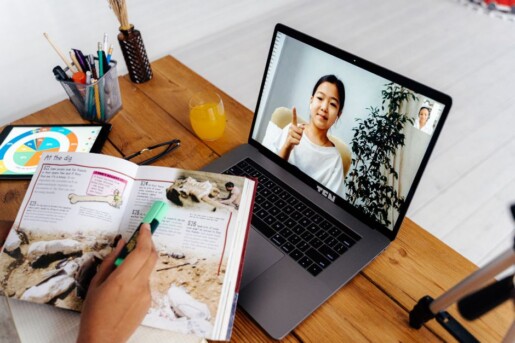 Pessoa criando infoproduto no notebook com anotações sobre impostos